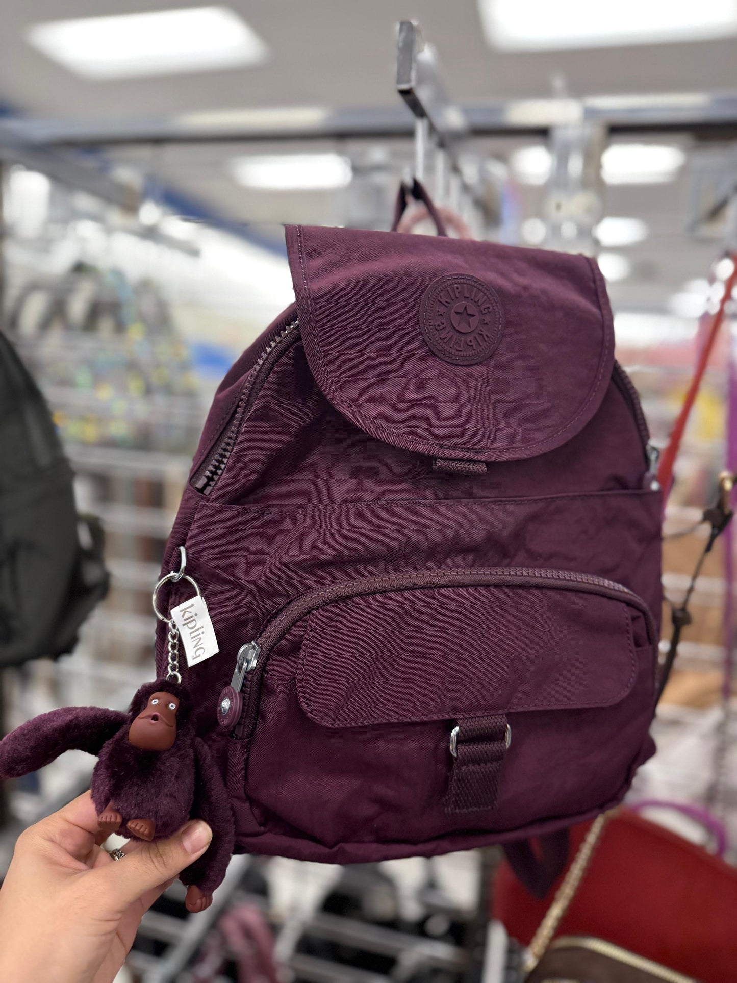 Backpack Kipling morada con changuito y placa de goma