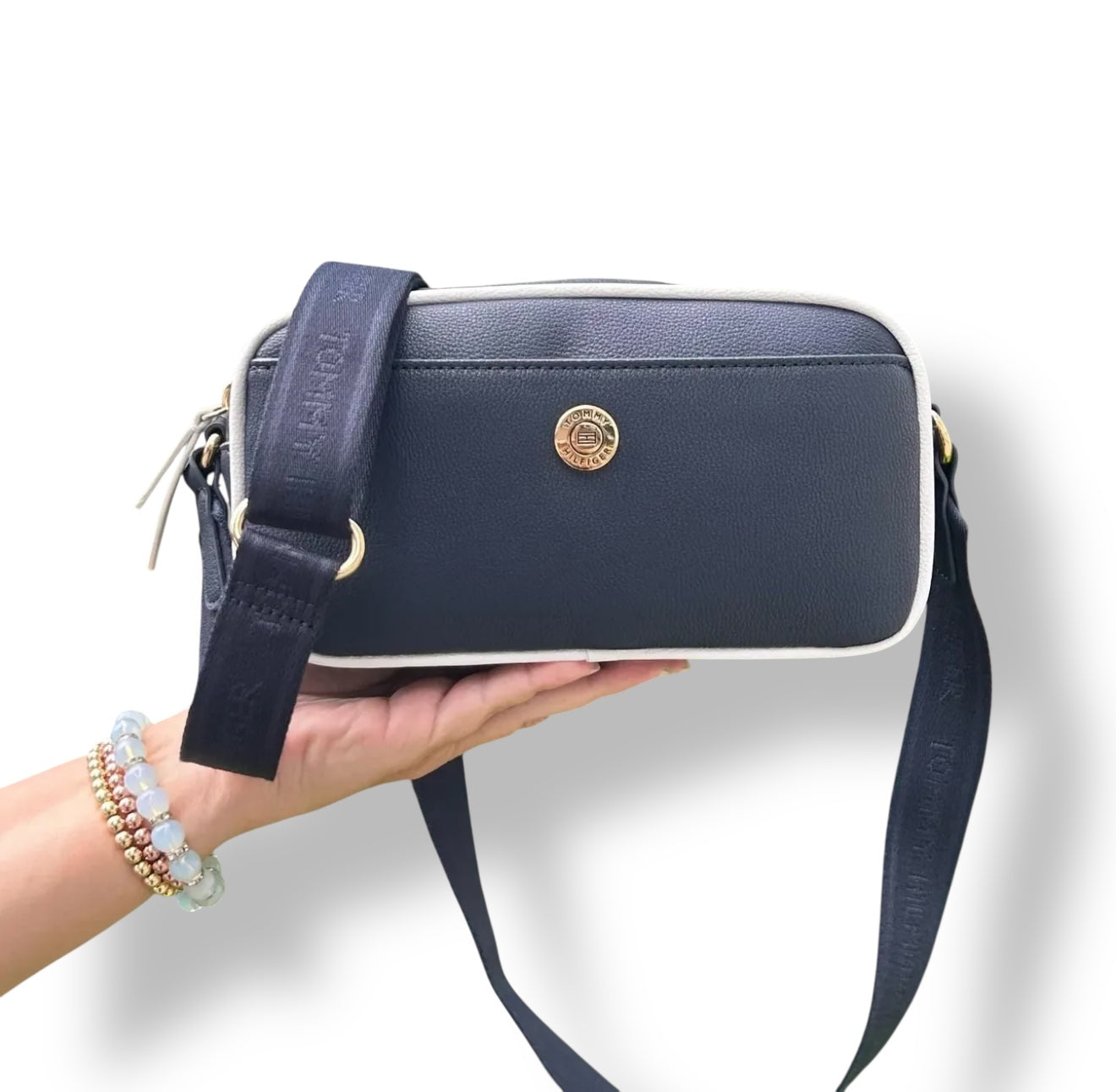 Crossbody Tommy H negra con contorno blanco y placa dorada redonda