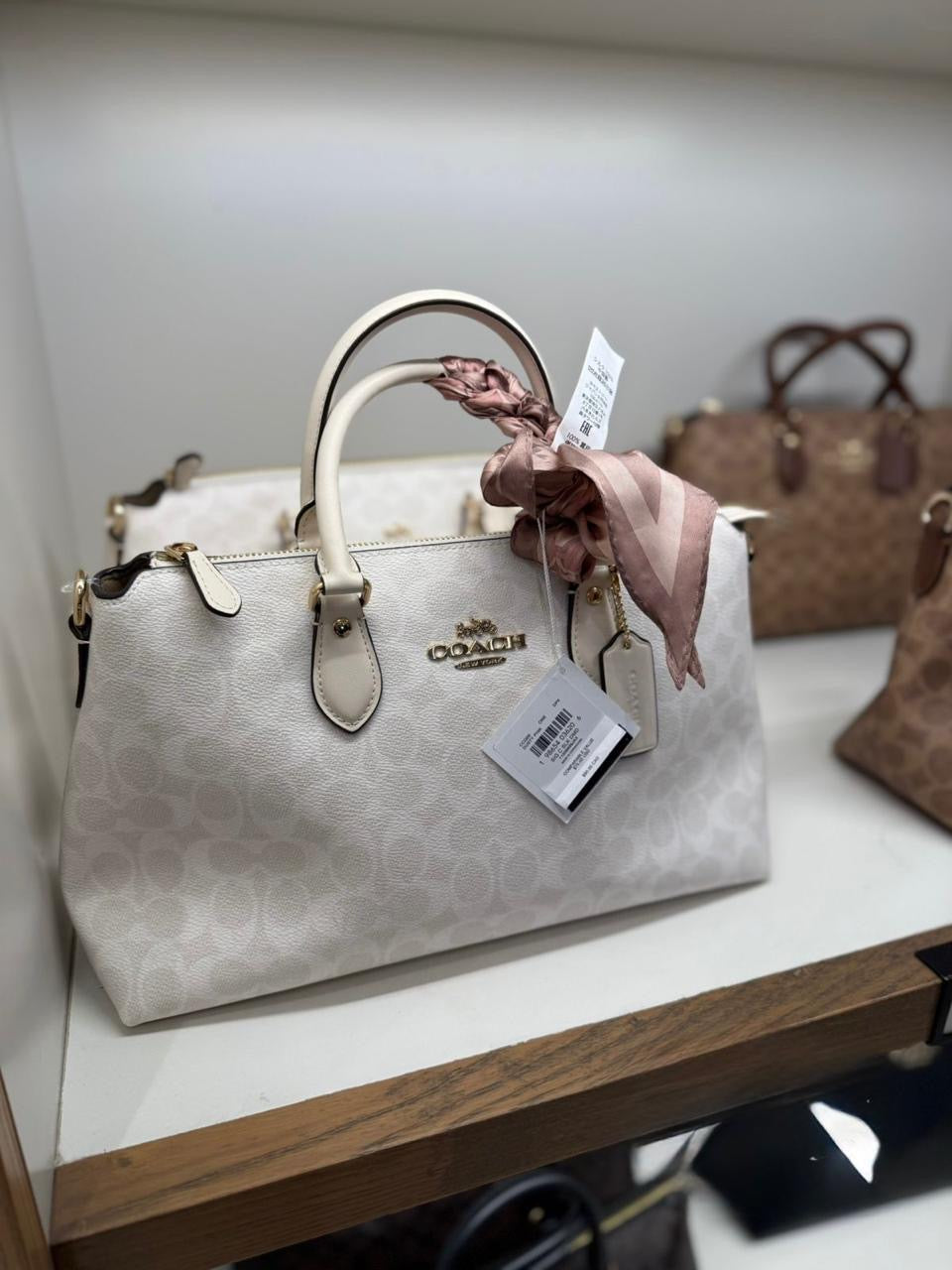 Crossbody Satchel Coach crema con canvas blancas, doble strap y placa dorada