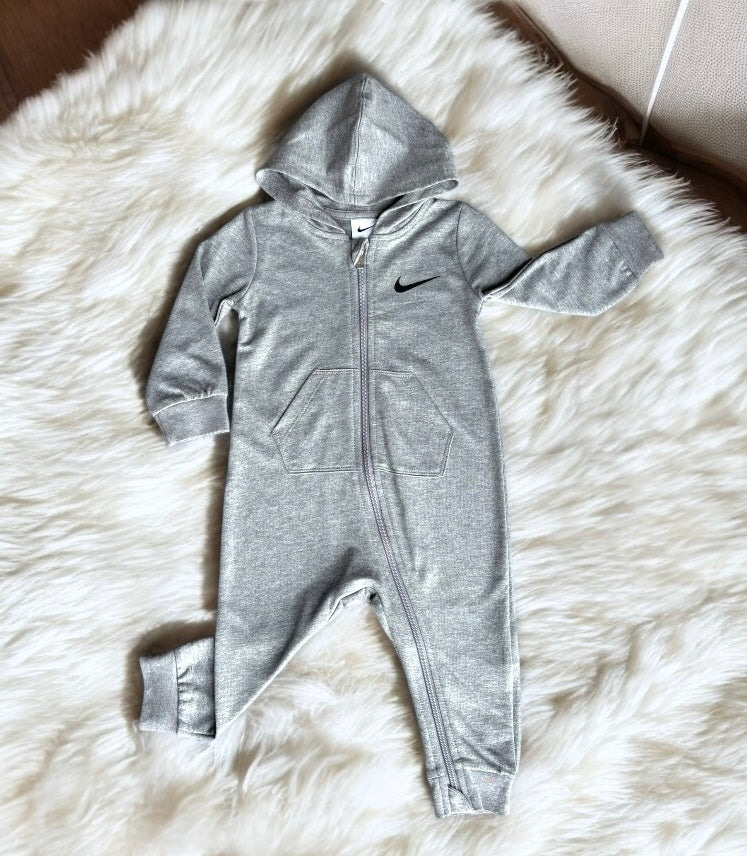 Mameluco Nike gris, cierre hasta el pie, capucha y logo chico negro