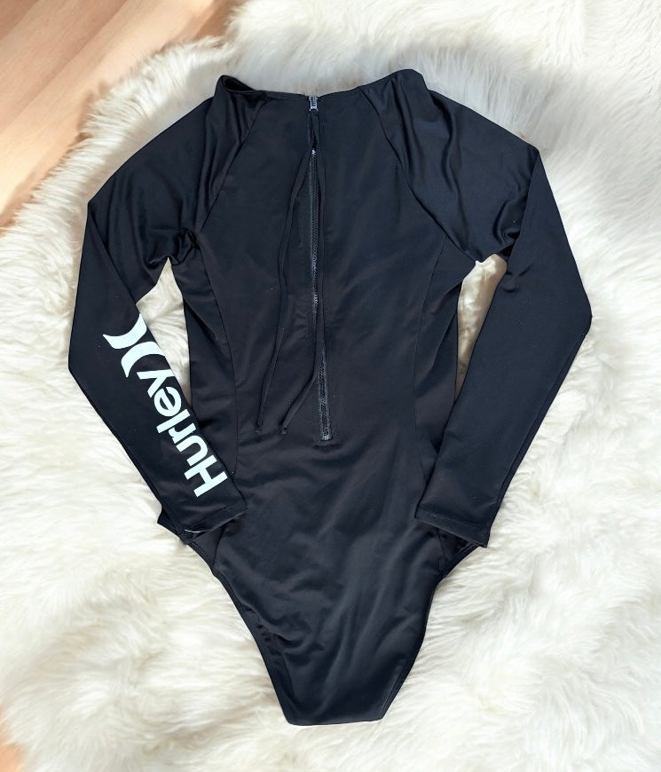 Traje de baño Hurley negro manga larga con cintas en el cuello y letras blancas en una manga