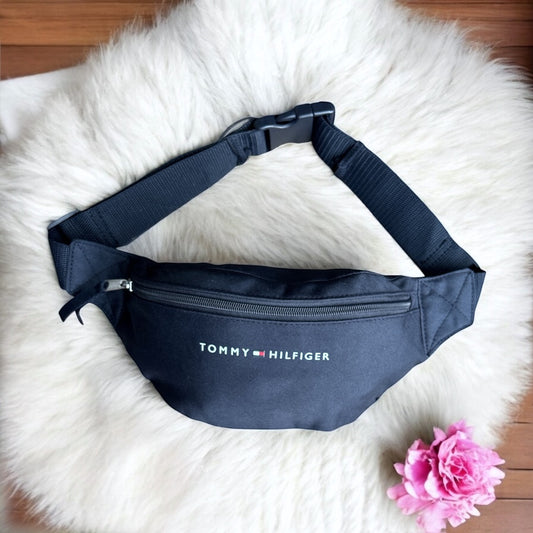 Cangurera Tommy H azul marino, strap ajustable, letras blancas y banderita
