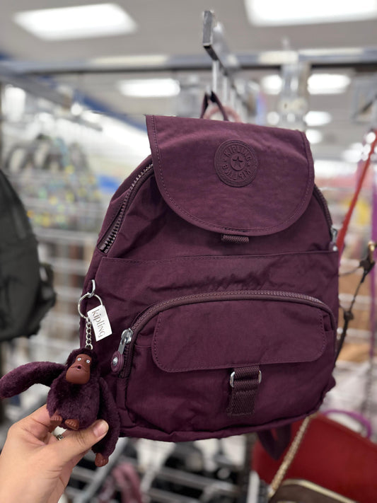Backpack Kipling morada con changuito y placa de goma