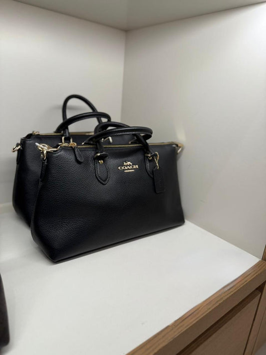 Crossbody Satchel Coach negra con textura, doble strap y placa dorada