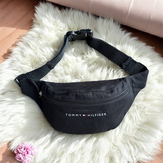 Cangurera Tommy H negra, strap ajustable, letras blancas y bandera pequeña