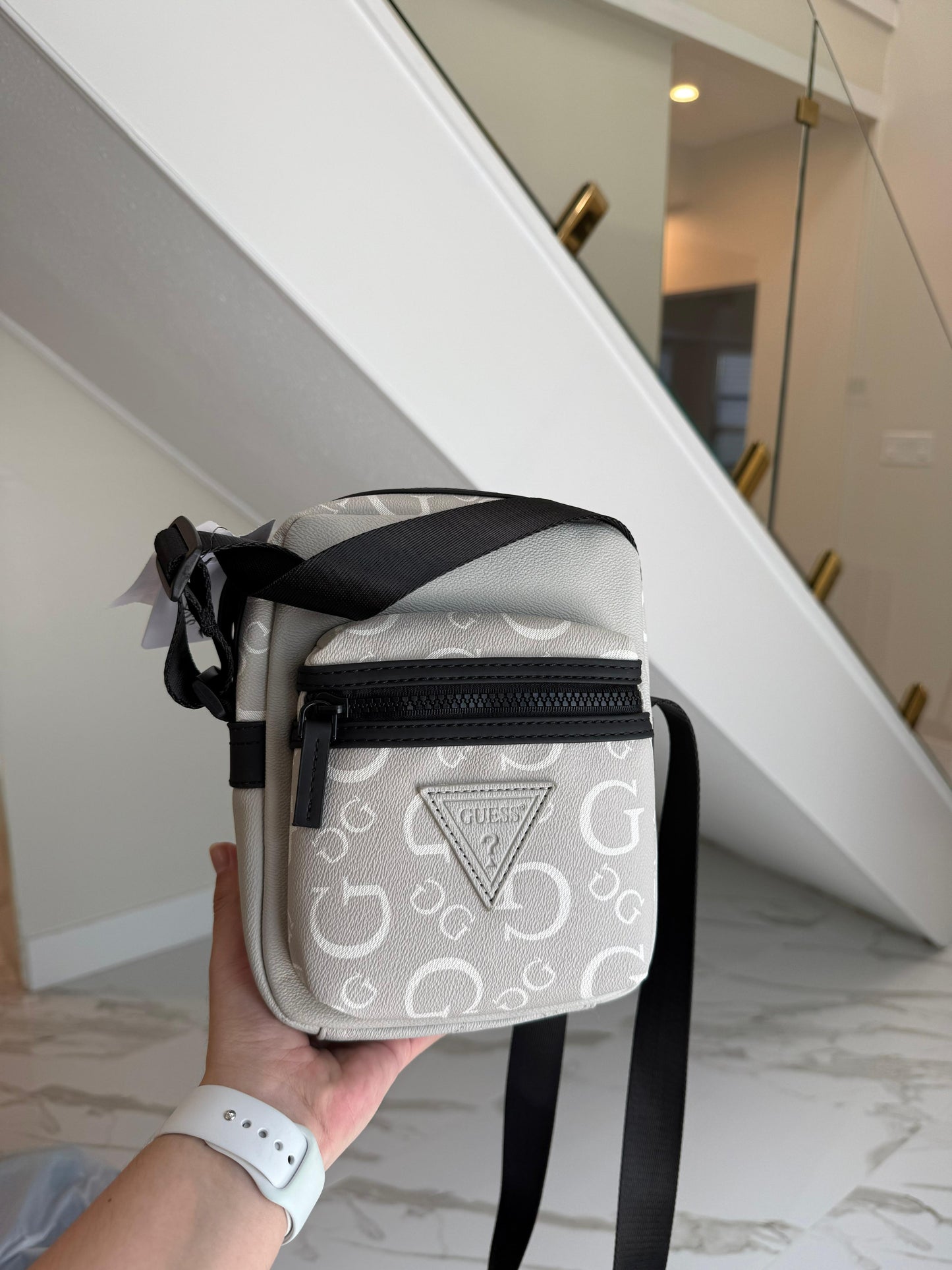 Bandolera Guess gris, monogram blanco detalles en negro y strap ajustable